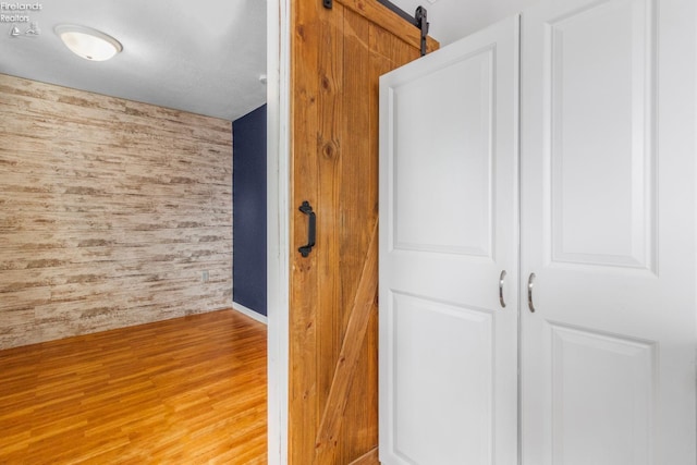 interior space featuring wooden walls, a barn door, and light wood-type flooring