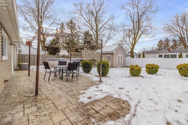 yard covered in snow featuring a shed and a patio area