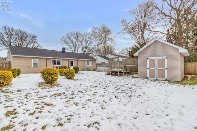 snow covered house with a shed and a wooden deck