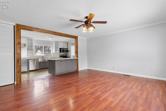 unfurnished living room featuring hardwood / wood-style flooring, ceiling fan, and ornamental molding