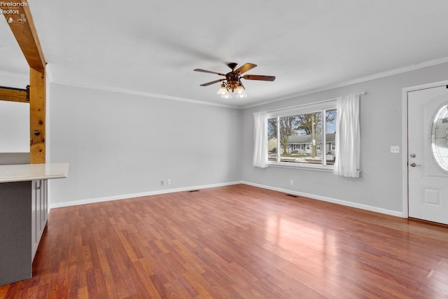 unfurnished living room with hardwood / wood-style flooring, ornamental molding, and ceiling fan