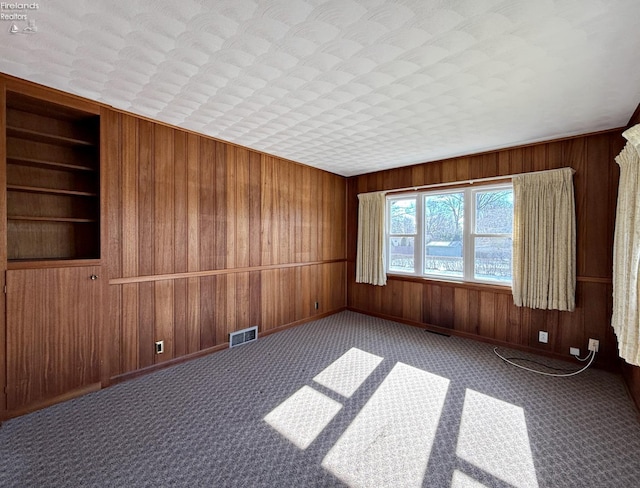 carpeted spare room with built in features and wooden walls