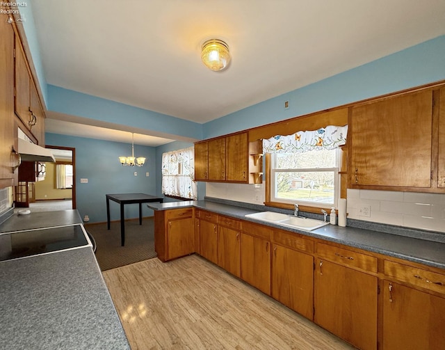 kitchen with sink, an inviting chandelier, hanging light fixtures, light wood-type flooring, and backsplash