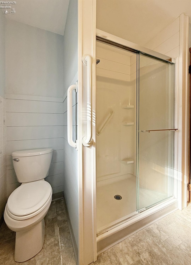 bathroom with a shower with door and toilet