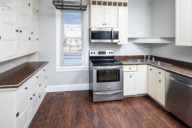 kitchen with appliances with stainless steel finishes, dark hardwood / wood-style floors, and white cabinets