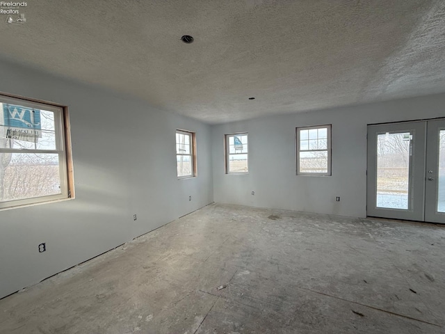 spare room with a wealth of natural light, a textured ceiling, and french doors