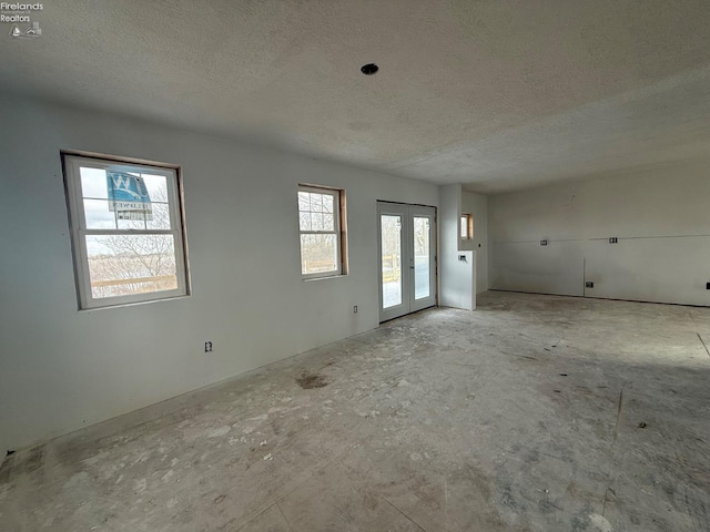 empty room with french doors and a textured ceiling