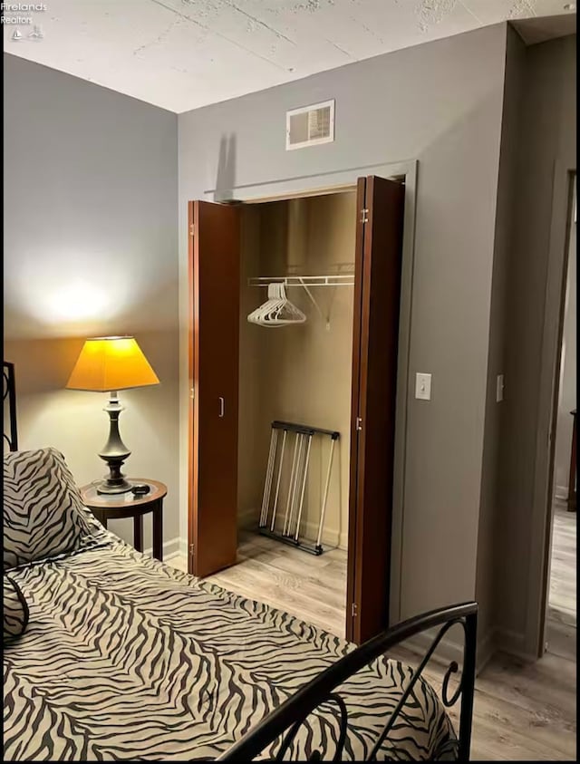 bedroom with light hardwood / wood-style floors and a closet