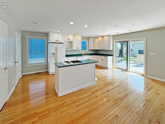 kitchen featuring sink, light hardwood / wood-style flooring, stovetop, white fridge with ice dispenser, and white cabinets