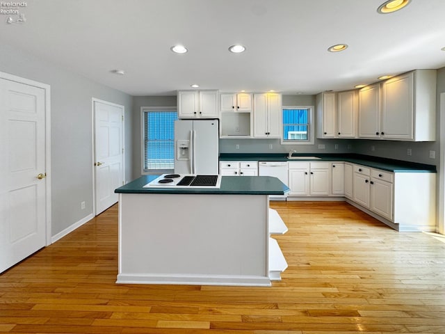 kitchen with white cabinetry, sink, white appliances, and light hardwood / wood-style flooring