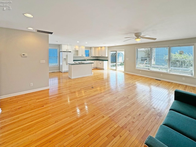 unfurnished living room featuring ceiling fan and light wood-type flooring