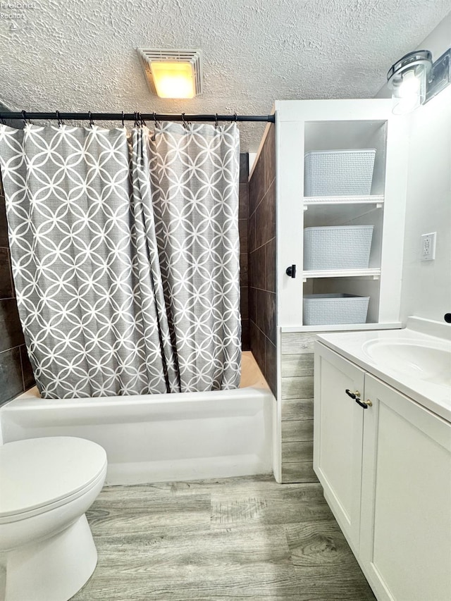 full bathroom with toilet, a textured ceiling, vanity, shower / bath combo with shower curtain, and hardwood / wood-style flooring