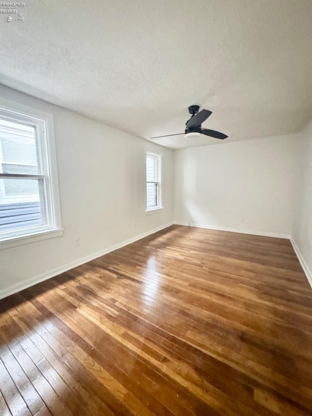 empty room with ceiling fan, dark hardwood / wood-style floors, and a textured ceiling