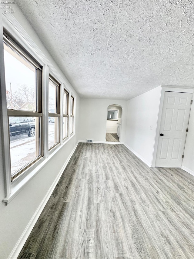 unfurnished living room with light hardwood / wood-style flooring and a textured ceiling