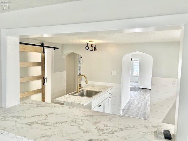 kitchen featuring white cabinetry, a barn door, sink, and a textured ceiling