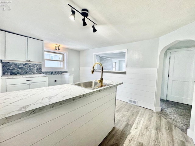 kitchen featuring sink, a textured ceiling, light hardwood / wood-style flooring, and white cabinets