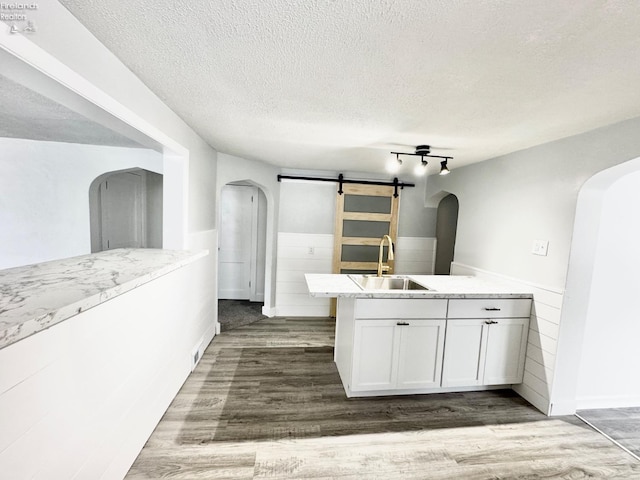 kitchen featuring a barn door, dark hardwood / wood-style floors, sink, and white cabinets