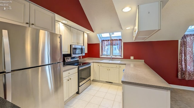 kitchen featuring appliances with stainless steel finishes, sink, white cabinets, light tile patterned floors, and kitchen peninsula