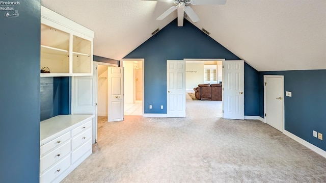 unfurnished bedroom featuring vaulted ceiling, light colored carpet, ceiling fan, and a textured ceiling