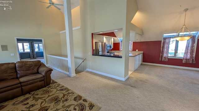 living room featuring ceiling fan, light colored carpet, and a high ceiling