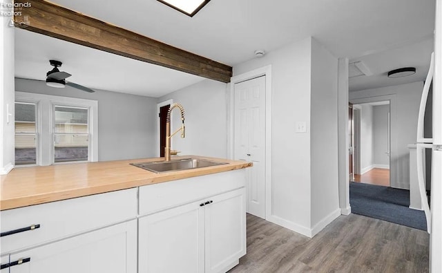 kitchen featuring sink, light wood-type flooring, ceiling fan, beam ceiling, and white cabinets