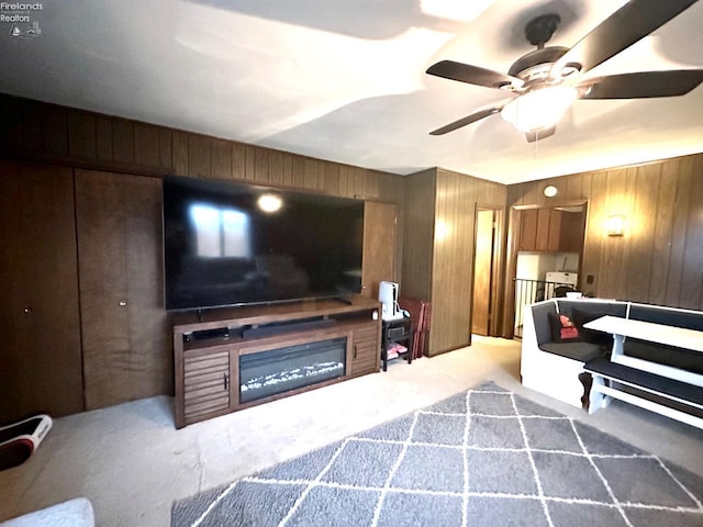 living room with carpet, ceiling fan, and wood walls