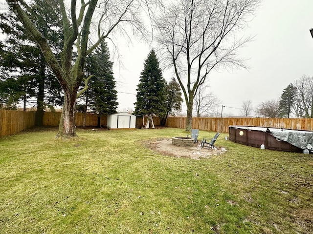 view of yard featuring a shed, a covered pool, and an outdoor fire pit