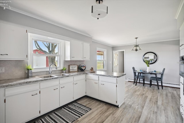 kitchen featuring a baseboard heating unit, hanging light fixtures, sink, and white cabinets