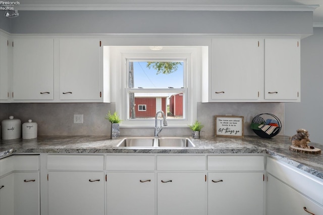 kitchen featuring backsplash, sink, and white cabinets