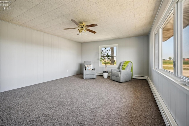 unfurnished room featuring a baseboard heating unit, ceiling fan, and carpet flooring