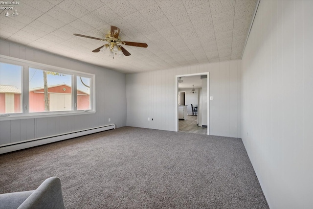 carpeted spare room featuring baseboard heating and ceiling fan