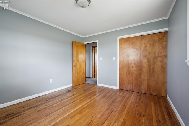 unfurnished bedroom featuring hardwood / wood-style flooring, ornamental molding, and a closet