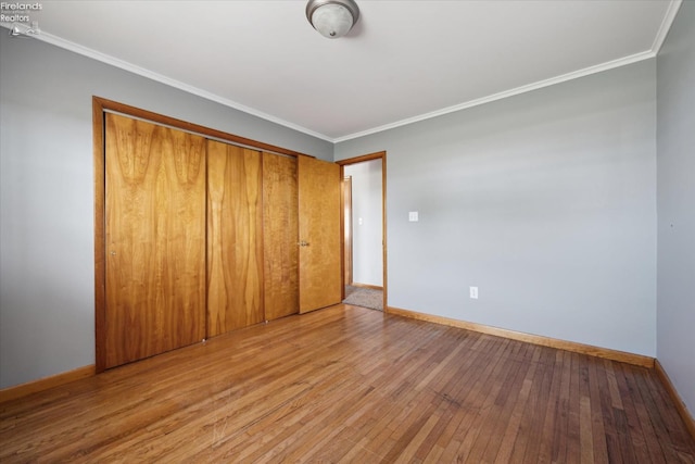 unfurnished bedroom with crown molding, light wood-type flooring, and a closet