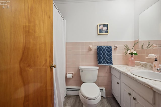 bathroom featuring vanity, a baseboard heating unit, toilet, and tile walls