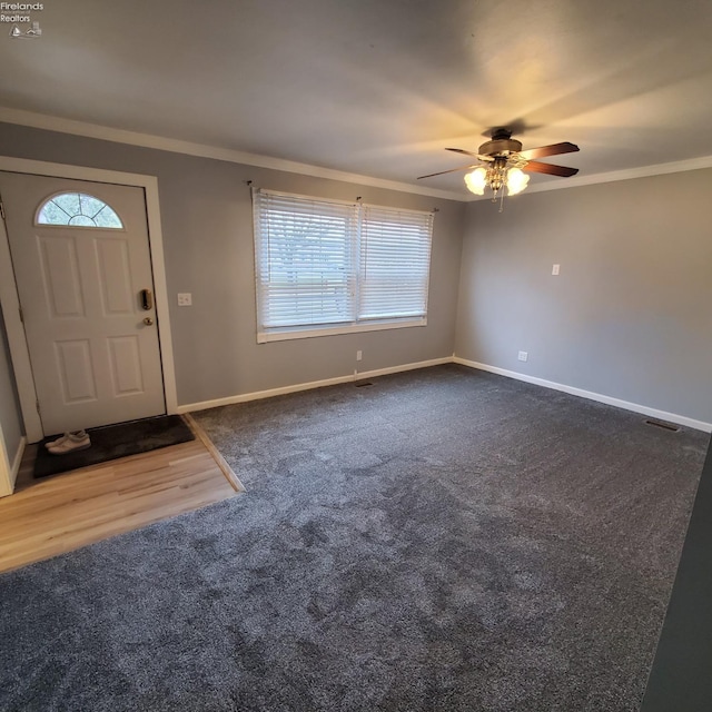 foyer entrance featuring ornamental molding, carpet flooring, and ceiling fan