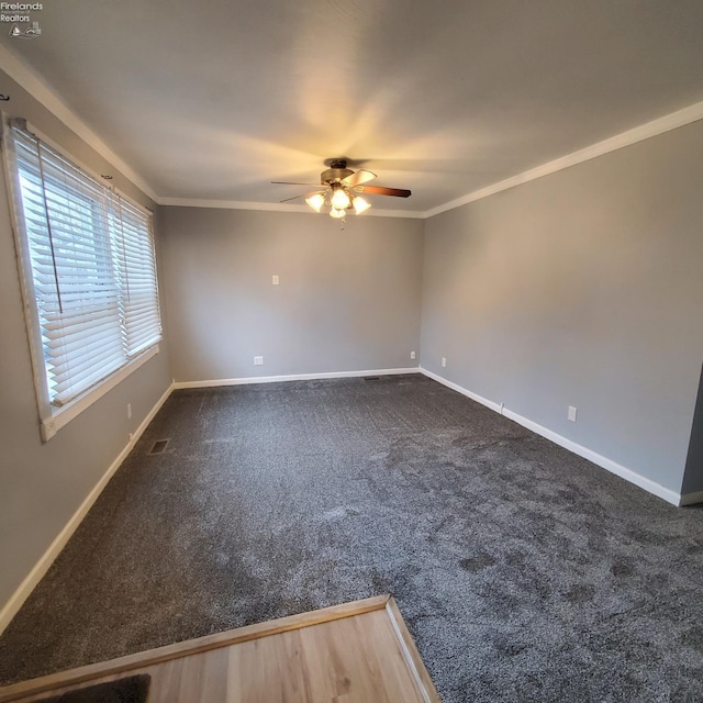 unfurnished room with ornamental molding, ceiling fan, and dark colored carpet