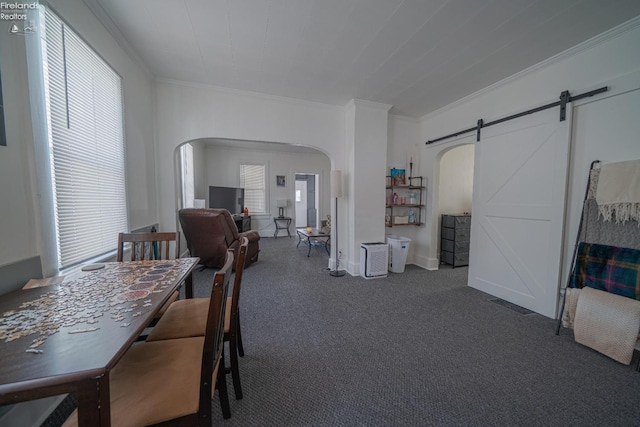 carpeted dining room featuring ornamental molding and a barn door