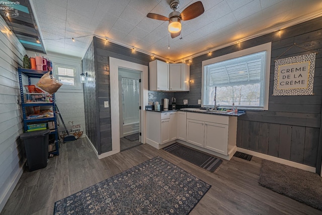 kitchen featuring white cabinetry, dark wood-type flooring, ceiling fan, and wood walls