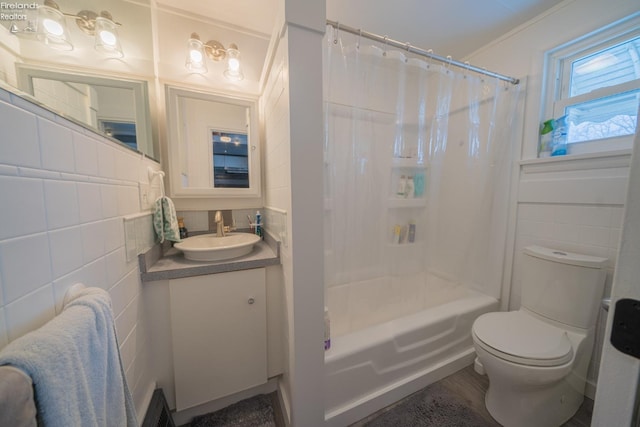 full bathroom featuring toilet, vanity, shower / bathtub combination with curtain, and tile walls