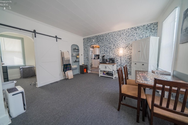 carpeted dining area with ornamental molding and a barn door