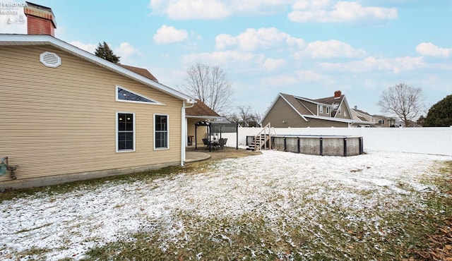 snowy yard featuring a fenced in pool and a patio