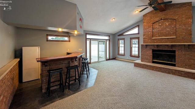 interior space featuring high vaulted ceiling, a baseboard radiator, dark colored carpet, ceiling fan, and a brick fireplace