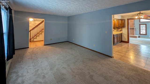 unfurnished living room with ceiling fan, light carpet, and a textured ceiling