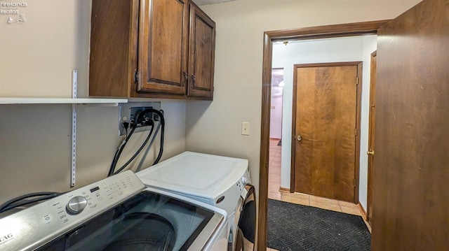 laundry room with cabinets, tile patterned floors, and washing machine and clothes dryer