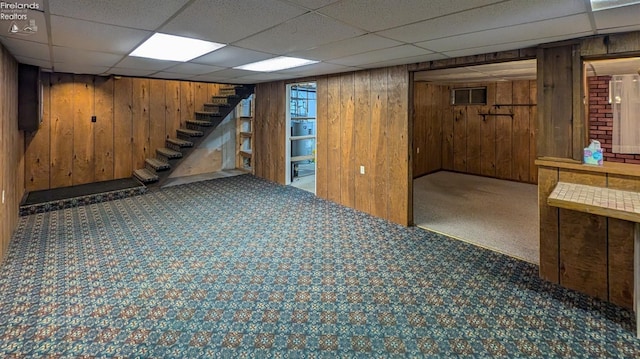 basement featuring wooden walls and dark colored carpet