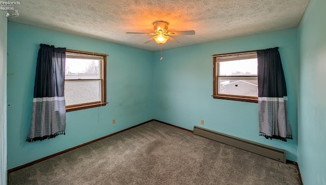 spare room featuring a baseboard radiator, carpet, a wealth of natural light, and ceiling fan