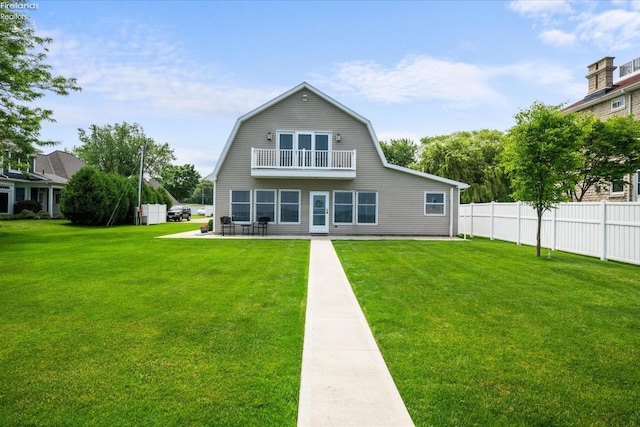 rear view of property featuring a lawn, a patio, and a balcony