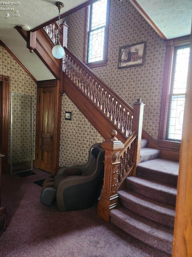 staircase with vaulted ceiling, carpet, plenty of natural light, and a textured ceiling