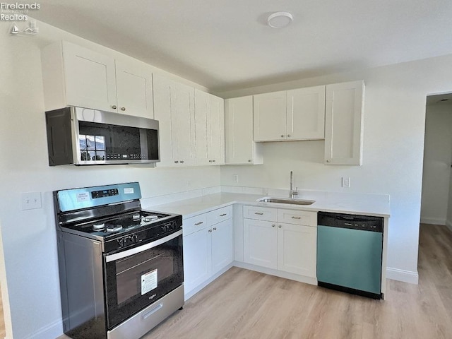 kitchen featuring stainless steel appliances, light hardwood / wood-style floors, sink, and white cabinets