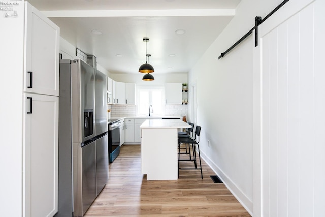 kitchen featuring sink, a breakfast bar, appliances with stainless steel finishes, white cabinetry, and a kitchen island